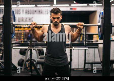 concentrated man athlete doing squats in a gym. front view Stock Photo