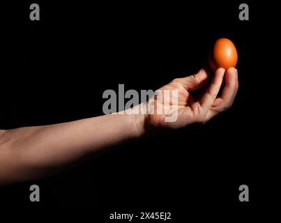 egg in hand on black background Stock Photo