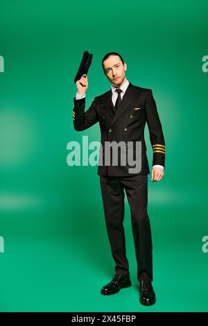 A stylish pilot in a black suit confidently waving with hat. Stock Photo