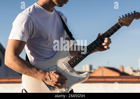 man playing electric guitar on a rooftop Stock Photo