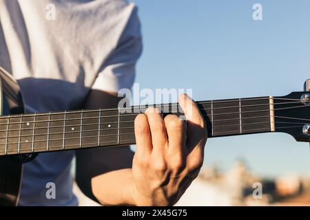 young man sitting playing acoustic guitar close-up Stock Photo