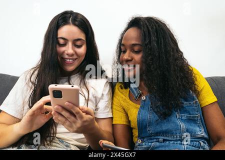 Connected at home: Two young women using mobile devices Stock Photo