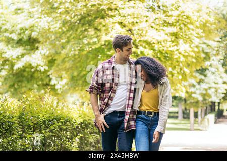 Happy multiracial young couple of Caucasian man and African American woman having a romantic walk in the park Stock Photo