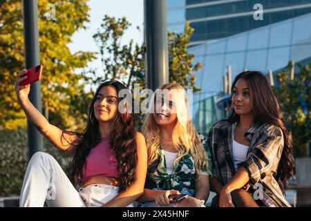 Three friends hanging out in the city, taking selfies with smartphone and having fun Stock Photo
