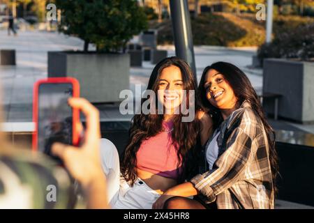 Crop of an unrecognizable woman taking photos with smartphone of her friends Stock Photo