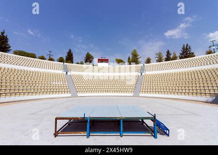 Open air public theater with perfect semicircular shape and many rows of white plastic chairs, in the island of Salamina, Greece. Stock Photo