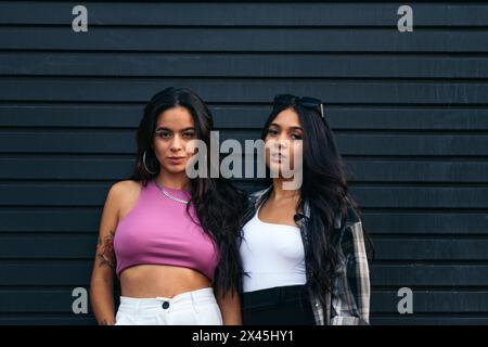Portrait of two young related latin women looking at camera with serious expression. Stock Photo