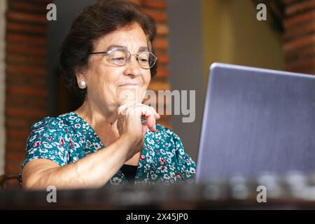 Image of a senior woman browsing the internet while using her laptop at home. Stock Photo