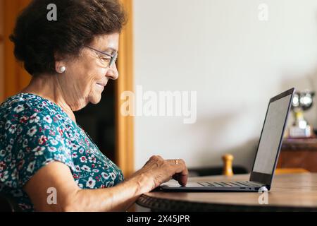 Image of a senior woman browsing the internet while using her laptop at home. Stock Photo
