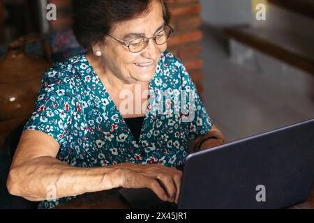 Image of a senior woman browsing the internet while using her laptop at home Stock Photo