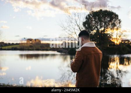 Young man using a drone near a lake to record and photograph the landscape. Stock Photo