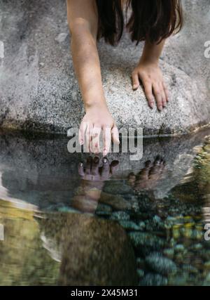 Close-up of a hand touching the river water. Concept of connection with nature Stock Photo