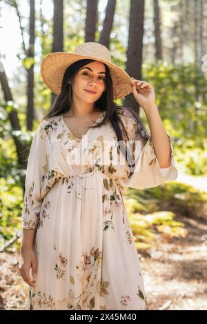 Beautiful brunette woman with a straw hat walking in the forest Stock Photo