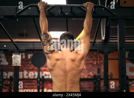back view of a strong man doing pull ups in a gym Stock Photo