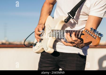 man playing electric guitar on a rooftop. close-up Stock Photo