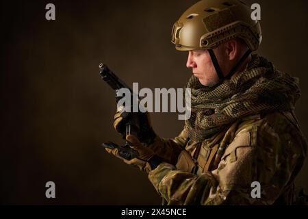 Portrait of man in military outfit reloading airsoft gun Stock Photo