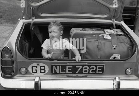 1960s, historical, an anxious little boy sitting with luggage in the open boot of a car of the era, a Ford Corsair. On the suitcases, luggage labels, stating Union-castle line/Safmarine, cruise ships operated by South Africa Marine Corporation, a South African shipping company based in Cape Town. Stock Photo