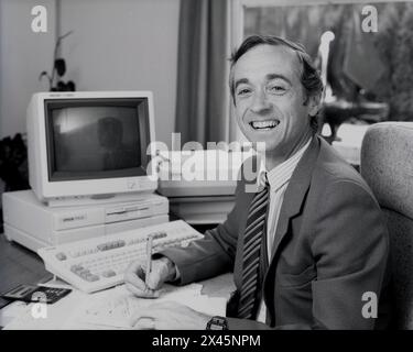 1987, a male business executive at his desk, a bookkeeper or accountant ...