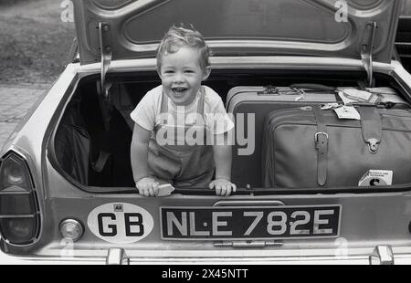 1960s, historical, a little boy holding a wafer standing with luggage in the open boot of a car of the era, a Ford Corsair. On the suitcases, luggage labels, stating Union-castle line/Safmarine. crusie shpips operated by South Africa Marine Corporation, a South African shipping company based in Cape Town. Stock Photo