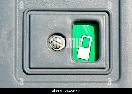 Close up of the lock on a portable toilet showing an open padlock on a green background to indicate that the door is unlocked and the unit vacant. Stock Photo