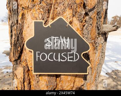 Stay focused symbol. Concept words Stay focused on beautiful black house blackboard. Beautiful tree background. Business, support, motivation, psychol Stock Photo