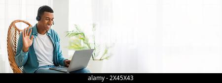 Man in headphones using laptop and waving Stock Photo