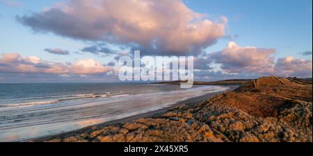 Aerial panorama landscape view of sand dunes and sandy beach at  Embleton Bay and Dunstanburgh Castle on the England Coast Path at sunset Stock Photo