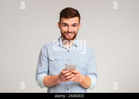 Young bearded man using his phone and smiling Stock Photo