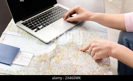Unrecognizable Woman Using Laptop Computer on Map Stock Photo