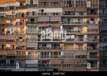 Balconies with belongings and drying clothes outside modern block of flats in at sunrise in city Stock Photo
