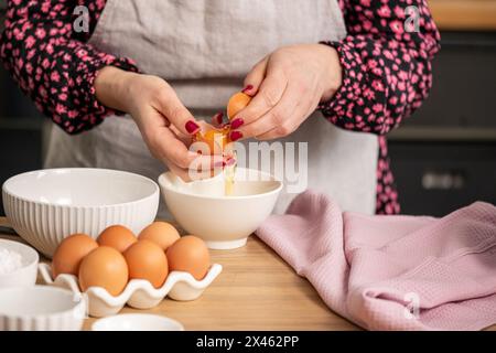 In a cozy kitchen, a cook skillfully separates an egg yolk from the white, surrounded by essential baking ingredients for a pastry recipe. High qualit Stock Photo
