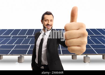 Happy businessman gesturing a thumb up sign in front of solar panel field isolated on white background Stock Photo