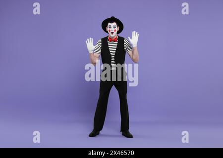 Mime artist making shocked face on purple background Stock Photo