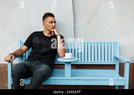 Handsome Lonely Man Sits Alone On A Bench And Drink Coffee Stock Photo