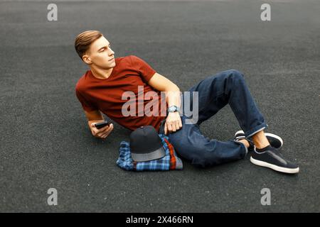 Handsome Man With Phone Lying On The Pavement And Rests. Stock Photo