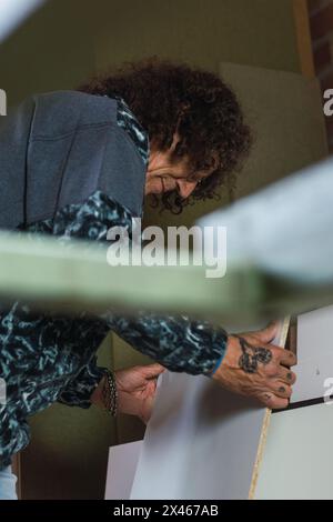 Side view low angle of mature male joiner working with piece of plywood in carpentry workshop Stock Photo