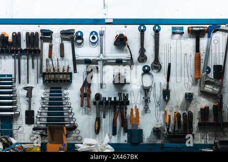 Set of screwdrivers and wrenches hanging on wall with assorted auto mechanic tools in garage Stock Photo