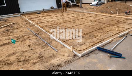 Wood frame and reinforcing steel rods or rebar used in preparation for concrete driveway at a construction job site. Stock Photo