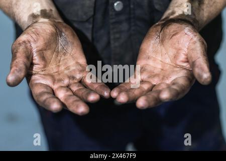 Anonymous mechanic showing dirty hands in car workshop Stock Photo