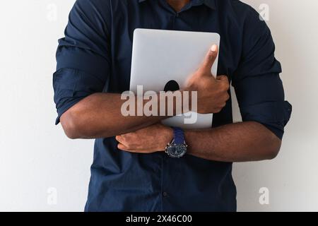 Crop African American adult male in formal clothes standing with netbook in hands on white background Stock Photo