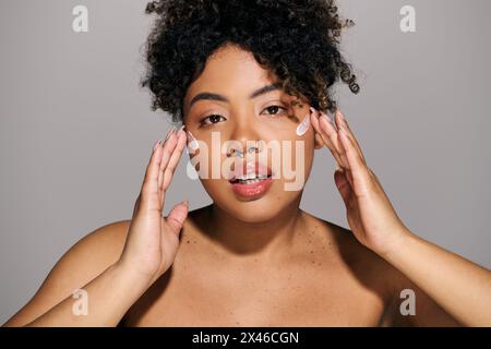 A young African American woman with curly hair holding her hands up to her face in a thoughtful pose. Stock Photo