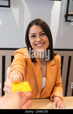 Cheerful female passing plastic card to crop unrecognizable waiter for making payment in cafe Stock Photo