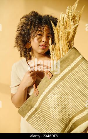 A beautiful young African American woman with curly hair holding a bag filled with a bunch of wheat. Stock Photo