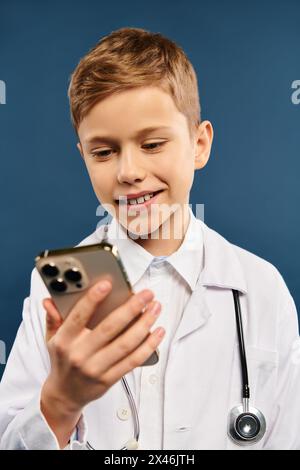 Boy in white doctors coat holds cell phone. Stock Photo