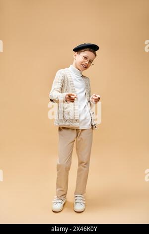 A cute preadolescent boy dressed as a film director on a beige backdrop. Stock Photo