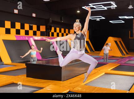 Adult woman trains jumping in trampoline center Stock Photo