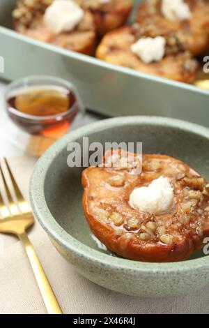 Tasty baked quince with nuts and cream cheese in bowl on table, closeup Stock Photo