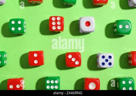Many color game dices on green background, flat lay Stock Photo