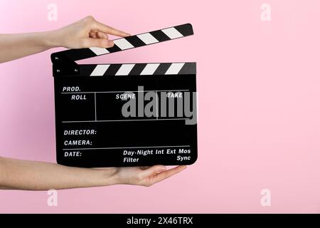 Woman holding movie clapper on pink background, closeup. Space for text Stock Photo