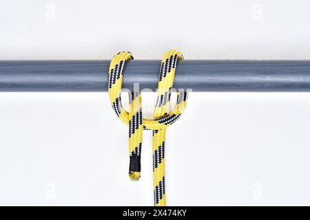 Clove hitch knot on yellow and black nylon rope on white background. Stock Photo